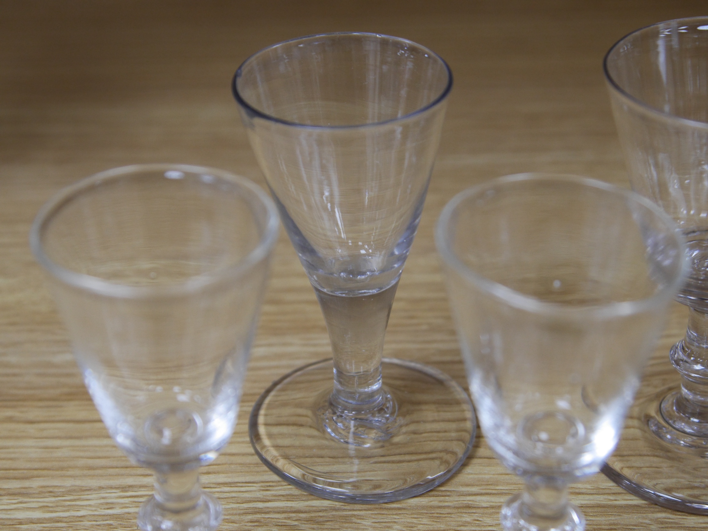 Four late 18th century ale wine and dram glasses, tallest 10.5cm. Condition - largest glass has a fine chip to rim